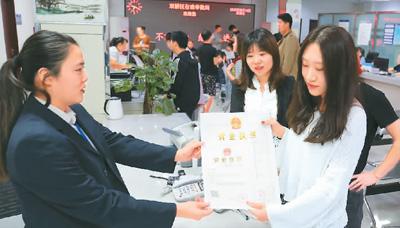 河北省承德市網(wǎng)絡(luò)代購經(jīng)營者陳晨(右)從工作人員手中接過帶有統(tǒng)一社會信用代碼的營業(yè)執(zhí)照。 劉環(huán)宇攝(人民圖片)